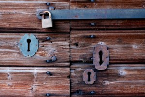Old wooden door with four locks cover by rust